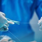 Surgery, hands and doctor cutting thread, stitching patient and surgical procedure with health insu
