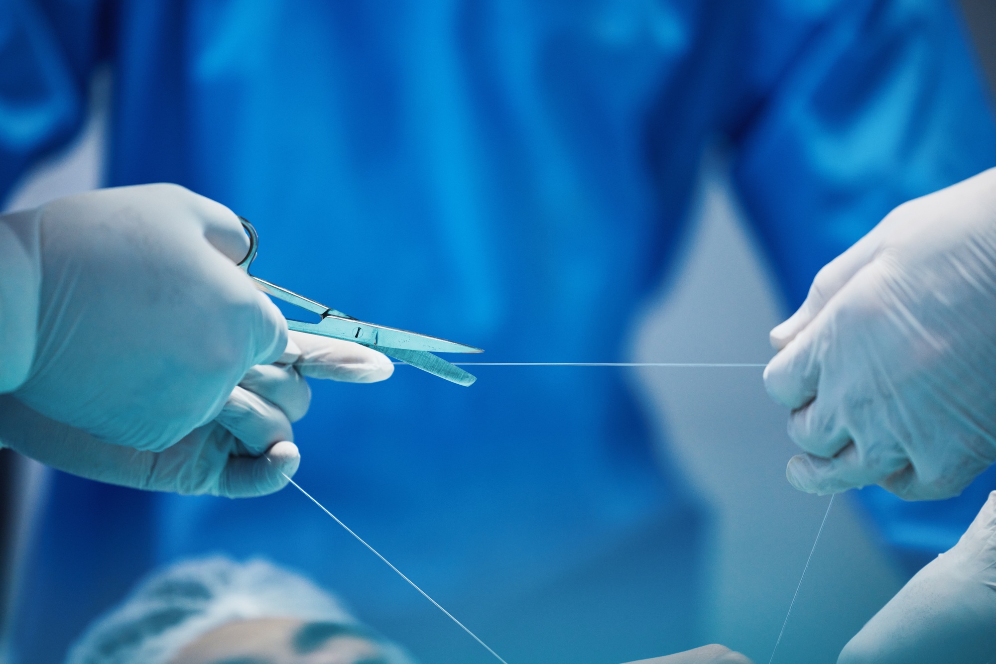 Surgery, hands and doctor cutting thread, stitching patient and surgical procedure with health insu