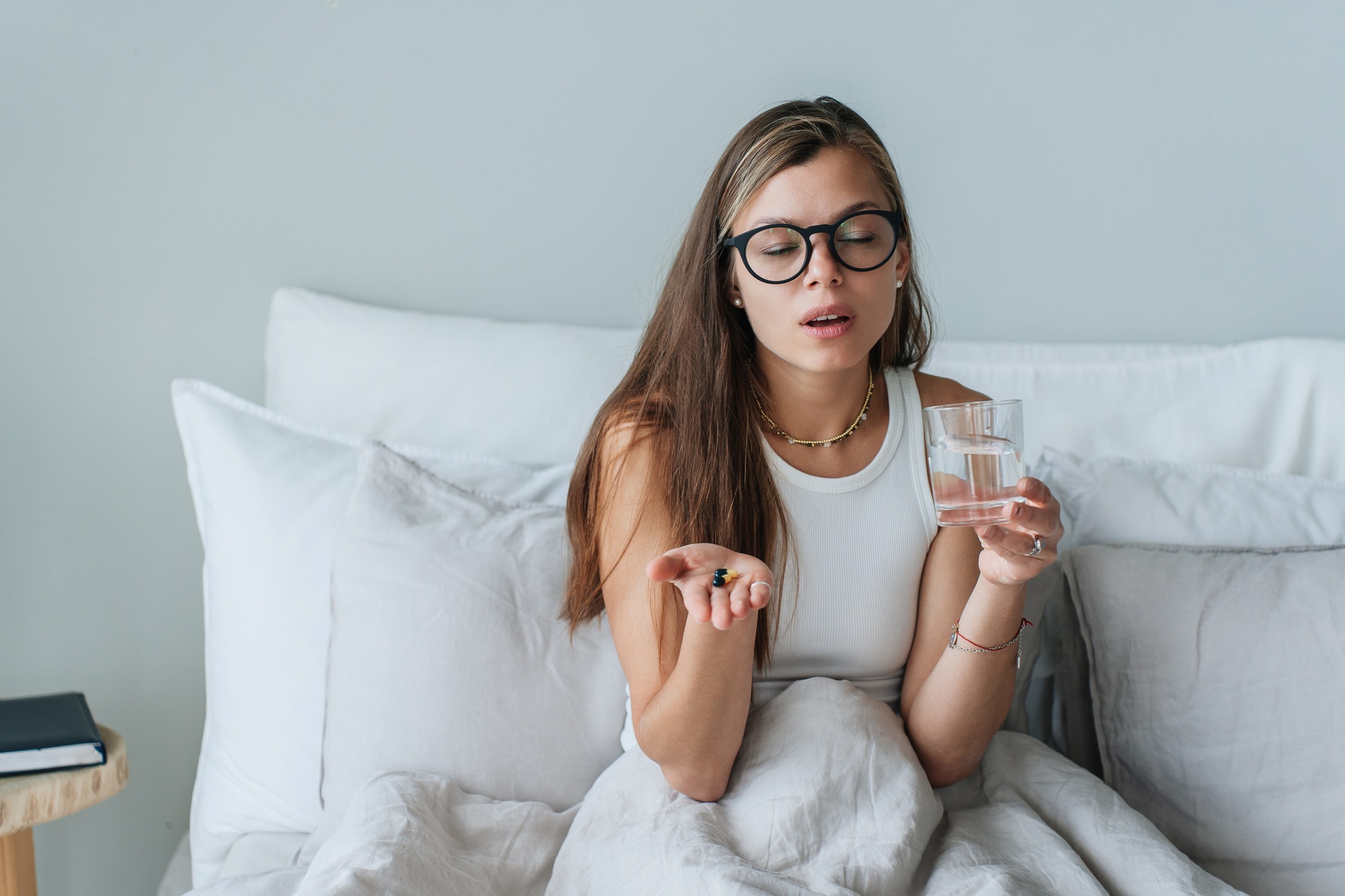 Young woman taking medicine in bed, morning healthcare routine